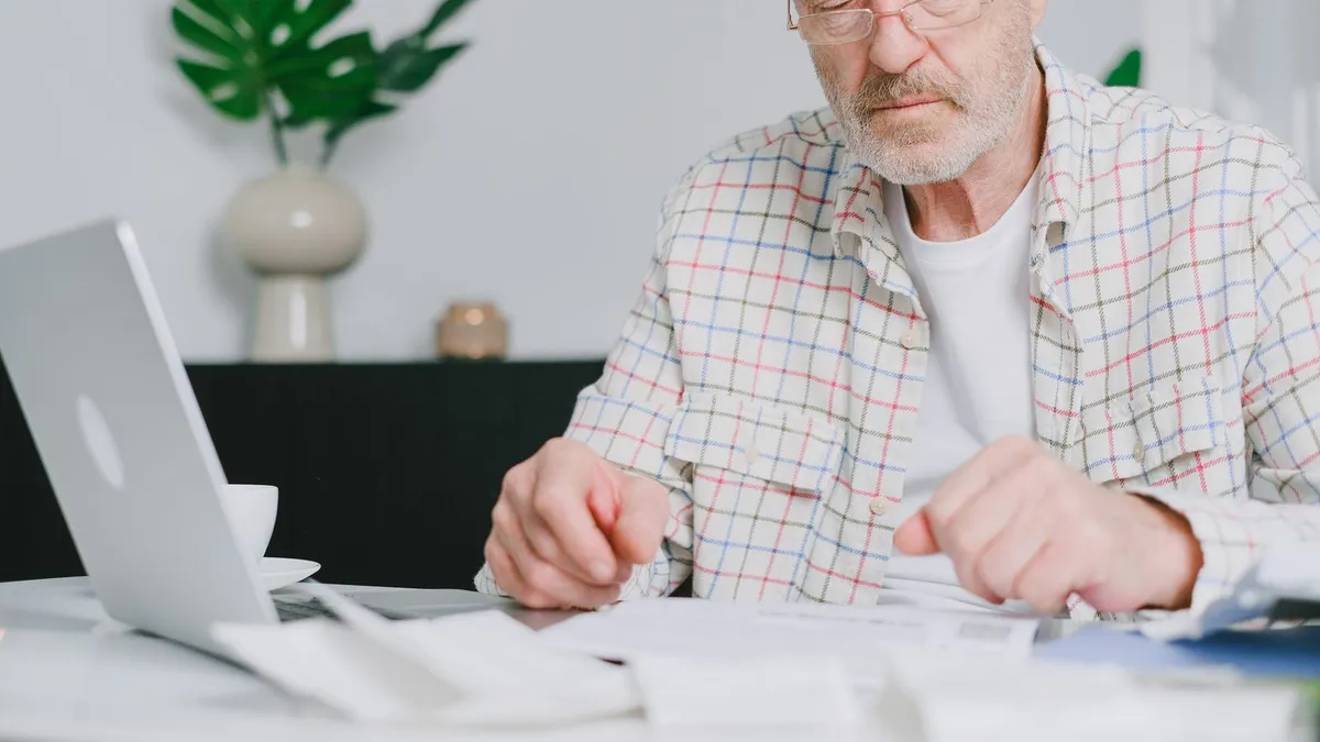 Retired man reading debt relief documents at a desk at home