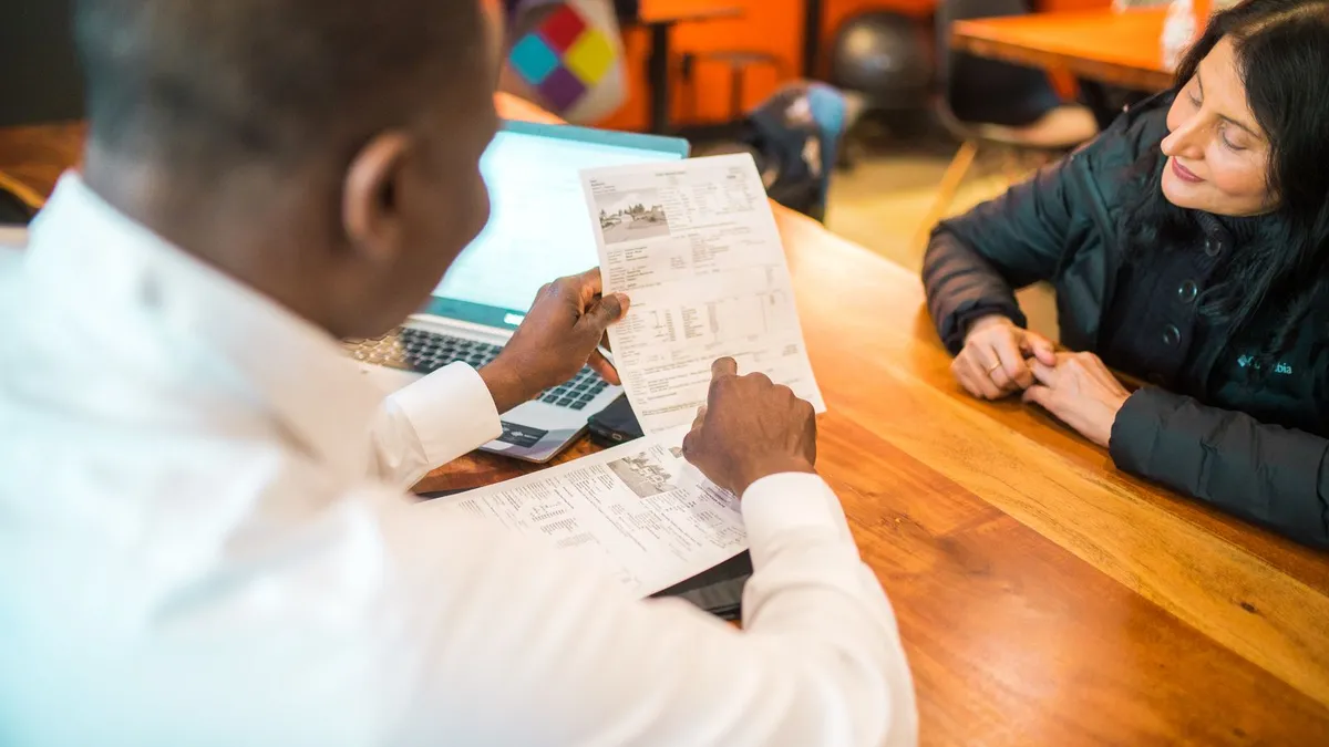 Advisor explaining national debt relief program options across a desk to a client with documents